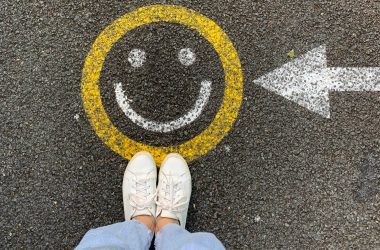 Woman standing by a smiley face graffiti on pavement